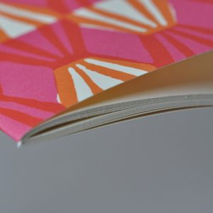 A detail of Exercise Book with Threadwork Pink and Orange patterned cover